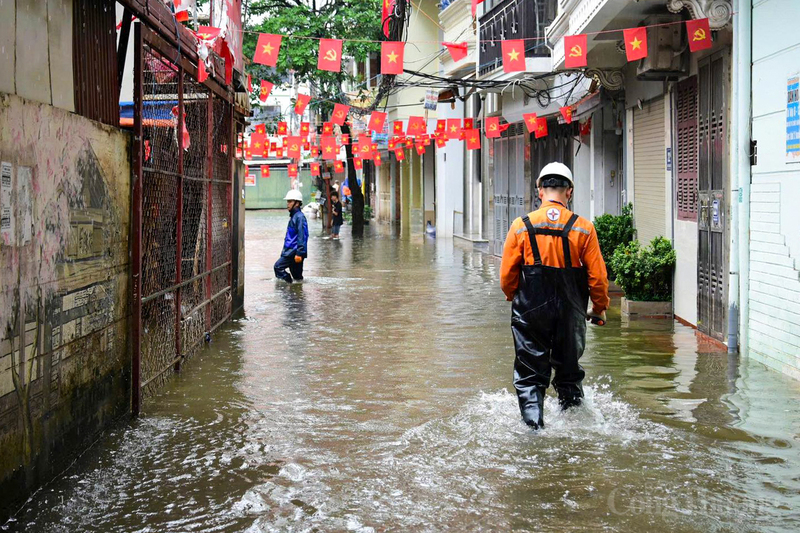 Cán bộ, nhân viên điện lực đi từng ngõ nhỏ bị ngập úng trên phố Đội Cấn để kiểm tra, hướng dẫn và nhắc nhở người dân bảo đảm an toàn điện.