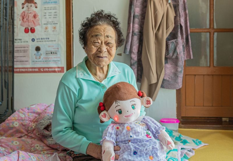 Một cụ bà đang ôm chú robot nhồi bông Hyodol được trang bị trí tuệ nhân tạo. Thiết bị này được thiết kế để ở bên cạnh những người sống một mình suốt 24 giờ mỗi ngày, cung cấp sự hỗ trợ về mặt tinh thần và theo dõi sức khỏe.