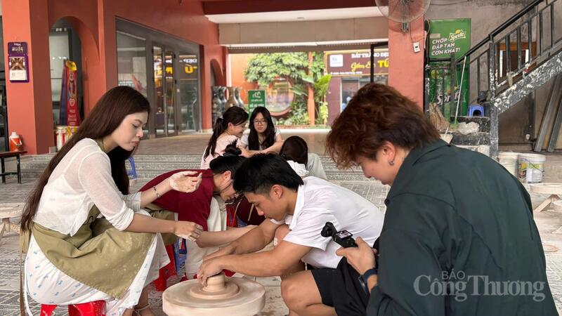 Du khách nước ngoài thích thú ghi lại khoảnh khắc làm gốm cùng bạn bè. Ảnh: Nhật Chi