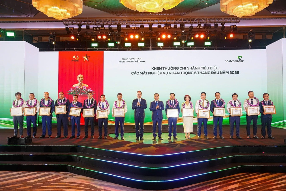 Ông Nguyễn Thanh Tùng - Bí thư Đảng ủy, Chủ tịch HĐQT Vietcombank (thứ 8 từ phải sang) tặng giấy khen và đ/c Lê Quang Vinh - Phó Bí thư Đảng ủy, Thành viên HĐQT, Tổng Giám đốc Vietcombank (thứ 9 từ phải sang) trao hoa chúc mừng cho 15 chi nhánh tiêu biểu trong hoạt động kinh doanh 6 tháng đầu năm 2026